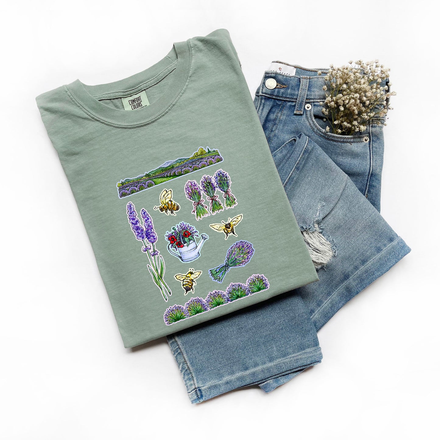 Folded green t-shirt with lavender farm and nature-themed design on a white background